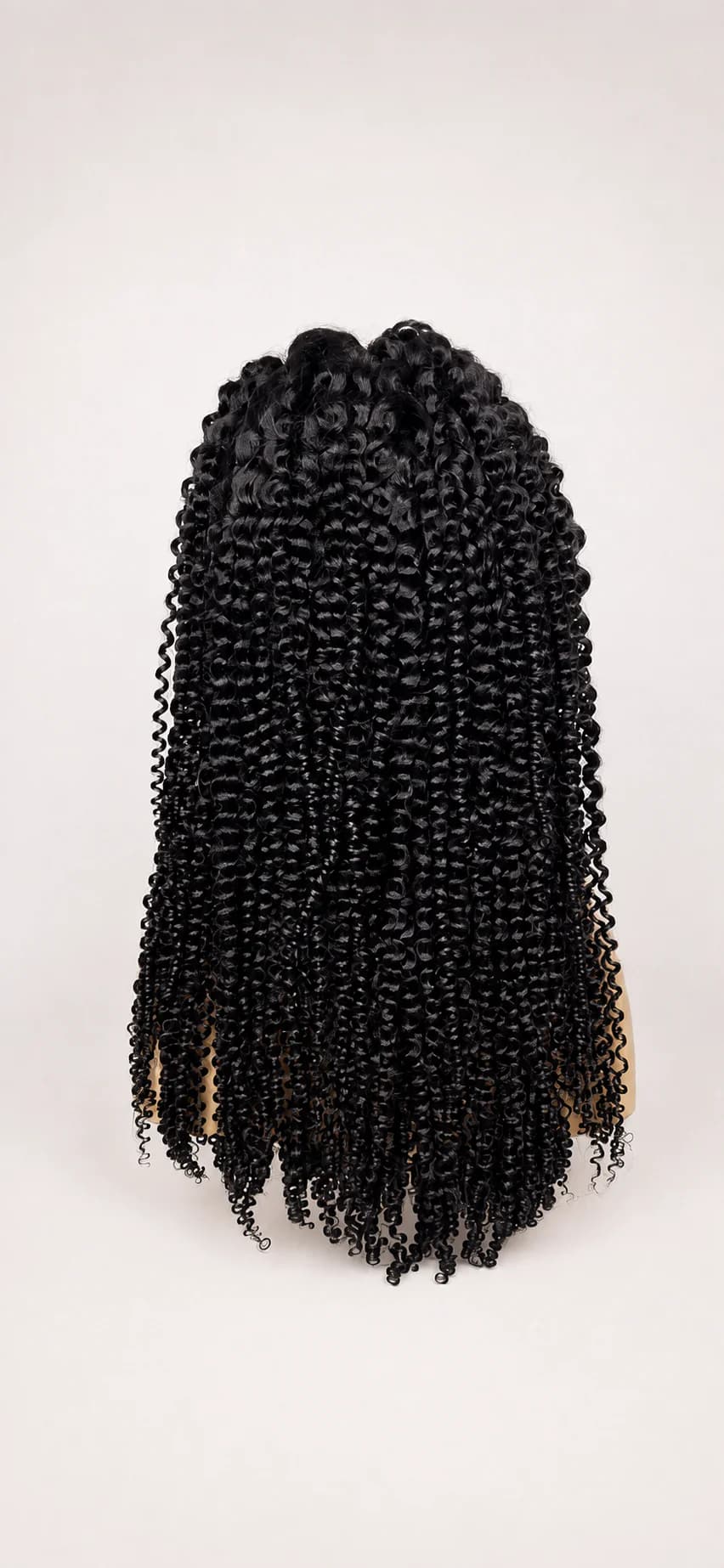 Dark kinky-curly wig on a clean cream background